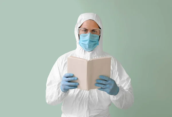 Man Biohazard Suit Reading Book Color Background — Stock Photo, Image