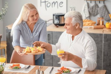 Mutlu yaşlı çift kahvaltısını evde yapıyor.