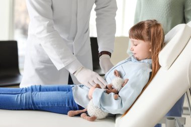 Gastroenterolog klinikteki küçük kızı muayene ediyor.