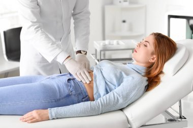 Gastroenterolog klinikteki kadını muayene ediyor.
