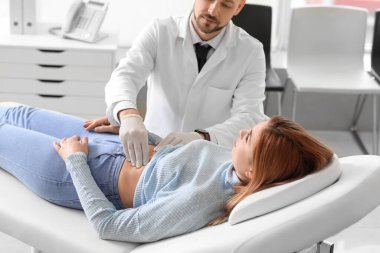 Gastroenterolog klinikteki kadını muayene ediyor.
