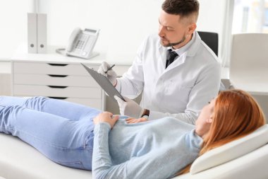 Gastroenterolog klinikteki kadını muayene ediyor.