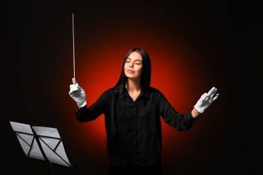 Young female conductor on dark background clipart