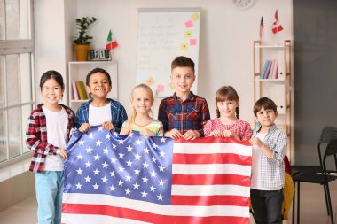 Dil okulunda Amerikan bayrağı taşıyan küçük çocuklar.