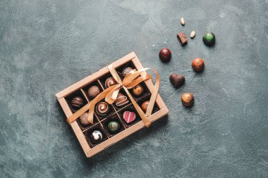 Karanlık arka planda lezzetli şekerlerle dolu bir kutu.