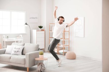 Yakışıklı adam dans ediyor ve evde müzik dinliyor.