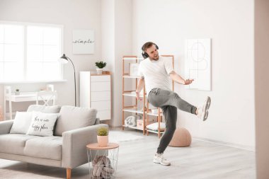 Yakışıklı adam dans ediyor ve evde müzik dinliyor.