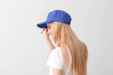 Hafif arka planda şık şapkalı güzel bir genç kadın.