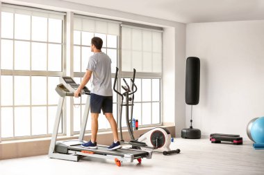 Genç adam spor salonunda koşu bandında antrenman yapıyor.