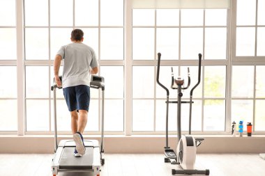 Genç adam spor salonunda koşu bandında antrenman yapıyor.