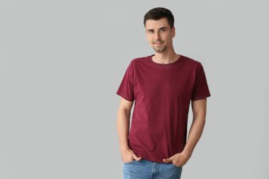 Gri arka planda şık tişörtlü adam.