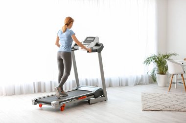 Spor kadın evde koşu bandında antrenman yapıyor.