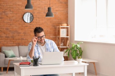 Evde çalışan dizüstü bilgisayarı olan adam.