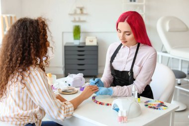 Manikür ustası kadın müşteriyle güzellik salonunda çalışıyor.