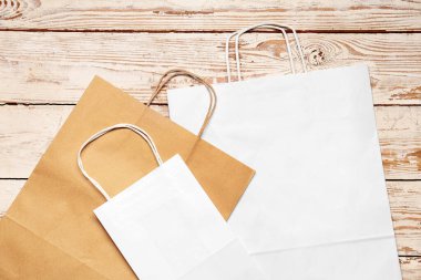 Beyaz ahşap arka planda kağıt alışveriş torbaları.