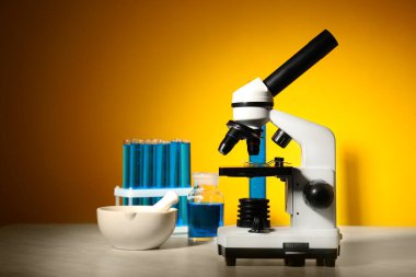 Modern mikroskop ve laboratuvar cam eşyalar masanın üstünde.