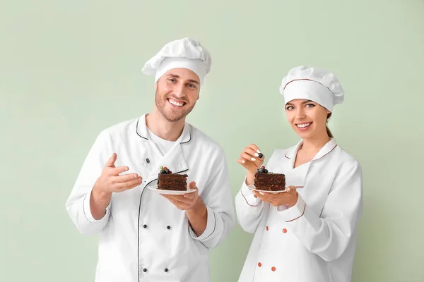 Pasteleros Jóvenes Con Sabroso Postre Sobre Fondo Color — Foto de Stock