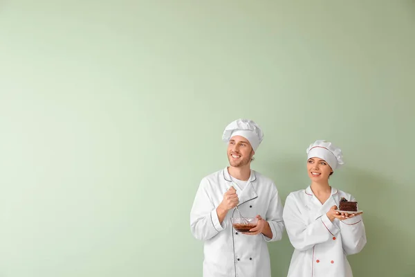 Pasteleros Jóvenes Con Sabroso Postre Sobre Fondo Color — Foto de Stock