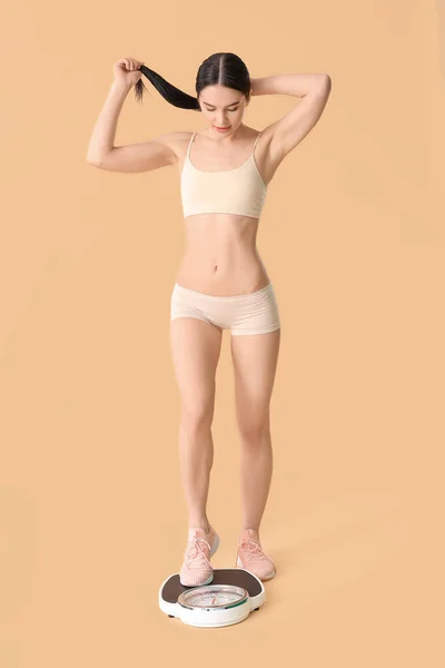年轻女子以肤色为背景测量自己的体重 — 图库照片