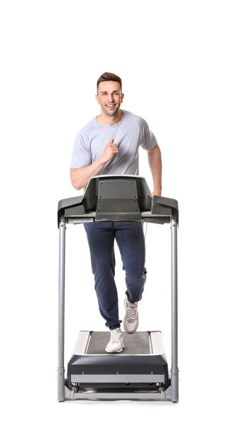 Sporty young man training on treadmill against white background