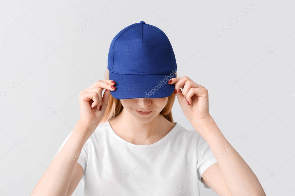 Beautiful young woman in stylish cap on light background