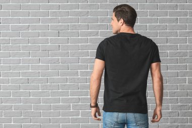 Tuğla arka planda şık tişörtlü adam