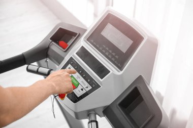 Genç adam spor salonunda koşu bandında antrenman yapıyor.