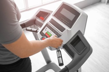 Genç adam spor salonunda koşu bandında antrenman yapıyor.