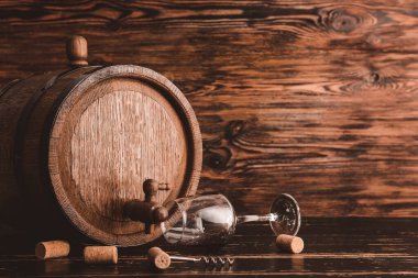 Masada tahtadan bir fıçı şarap ve cam var.