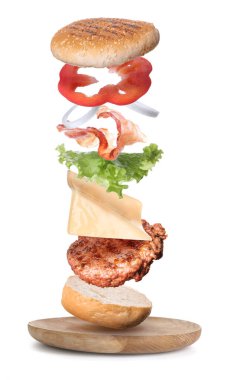 Beyaz arka planda uçan hamburgerler içeren bir tabak.