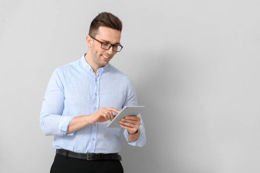 Hafif arka planda tablet bilgisayar ile Yakışıklı işadamı