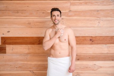 Yakışıklı adam ahşap arka planda duş alıyor.