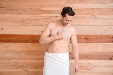 Yakışıklı adam ahşap arka planda duş alıyor.