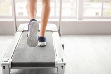 Genç adam spor salonunda koşu bandında antrenman yapıyor.