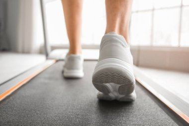 Genç adam spor salonunda koşu bandında antrenman yapıyor.