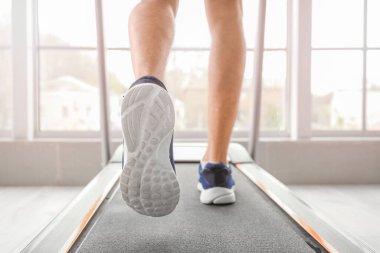 Genç adam spor salonunda koşu bandında antrenman yapıyor.