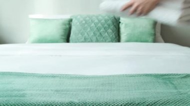 Oda hizmetçisi otel odasındaki yatağa temiz yumuşak havlular koyuyor.