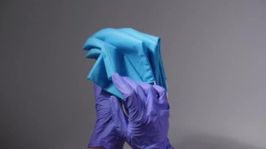 Gri arka planda koruyucu maskeli bir tıp çalışanı.