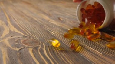 Ahşap arka planda balık yağı kapsüllerinin dağılması