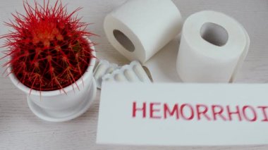 Kaktüs, fitil ve tuvalet kağıdı ile masaya HEMORRHOID kelimesi ile kağıt koymak