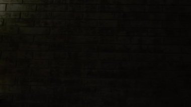 Karanlık odada, tuğla duvarın yanında parlayan lamba.