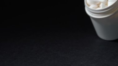 Karanlık arka planda haplarla şişeyi düşürmek.