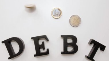 Işık arkaplanı üzerinde DEBT sözcüğü olan bozuk paralar, üst görünüm