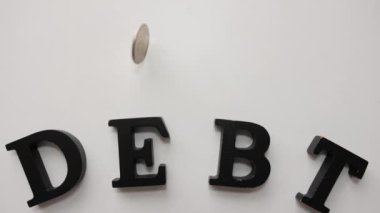 Açık arkaplanda DEBT sözcüğüyle bozuk para döndürme, üst görünüm