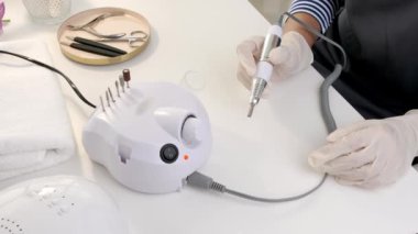 Manikür ustası güzellik salonunda modern değirmenciyle çalışıyor.