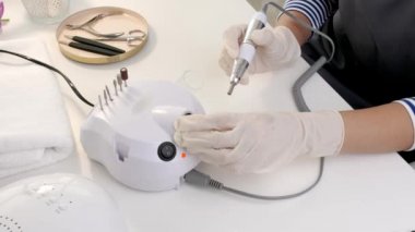 Manikür ustası güzellik salonunda modern değirmenciyle çalışıyor.