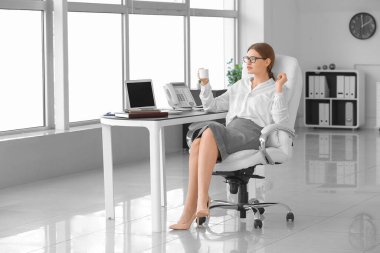 Güzel sekreter ofiste kahve içiyor.