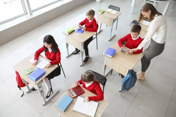 Children with math teacher during lesson in classroom