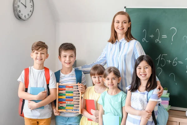 Children with math teacher during lesson in classroom