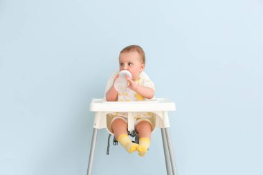 Şişe ile beslenme sandalyesinde oturan sevimli küçük bebek.